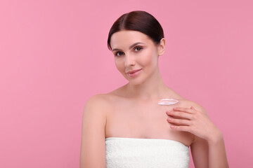 Beautiful woman with smear of body cream on her collarbone against pink background