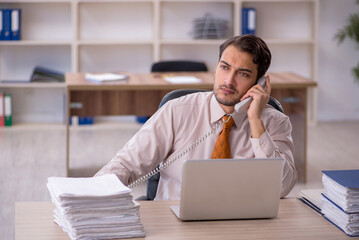 Obraz premium Young male employee and too much work in the office