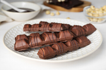 Tasty chocolate bars on white wooden table, closeup