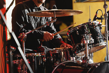 Close-up of drummer drumsticks with a drum set.