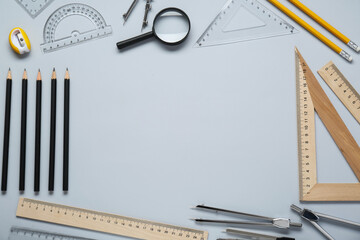 Flat lay composition with different rulers and compasses on light grey background. Space for text - obrazy, fototapety, plakaty