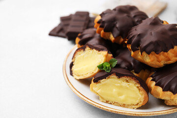 Delicious profiteroles with chocolate spread and cream on white table, closeup. Space for text