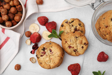 Cookies with freeze dried fruits, nuts and mint on white table, flat lay