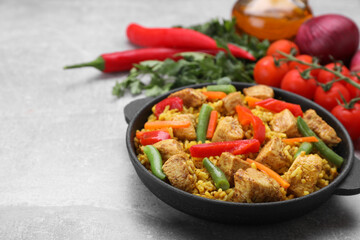 Serving pan of delicious rice with chicken and vegetables on light grey table, closeup. Space for text