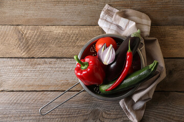 Fresh vegetables for ratatouille in colander on wooden table, flat lay. Space for text