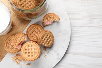 Tasty sandwich cookies with cream on white wooden table, flat lay. Space for text