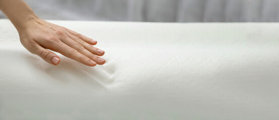 Woman touching memory foam pillow indoors, closeup. Banner design with space for text
