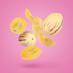Fresh ripe pepino melons falling on bright pink background