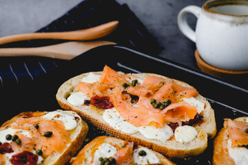 Smoked salmon toasted on sourdough with cheese and sun-dried tomato. Healthy eating, appetizer food, and bread concept. Cooking and gourmet concept