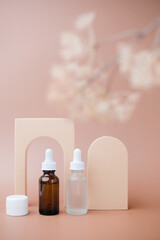 Two skincare dropper container bottles with decoration display and flowers. Cosmetic and beauty mock-up background.