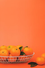 the vertical view of orange in the basket on bright orange background. with copy space