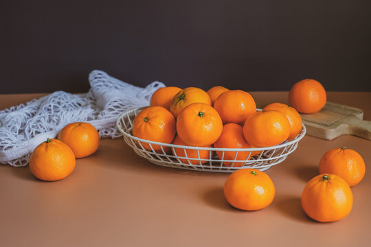 Mandarin or orange in the basket with fruit bag and wooden plate on the orange table top and black background.