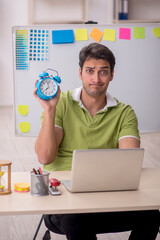 Young male designer in time management concept