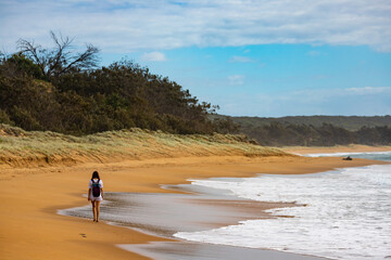 Fototapeta na wymiar backpacker girl walking on the tropical beach in queensland, australia; hiking in gladstone region near agnes water and town of 1770; deepwater national park