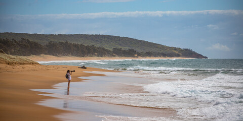 wildlife photographing girl taking photos of marine birds from the beach in deepwater national park, queensland, australia