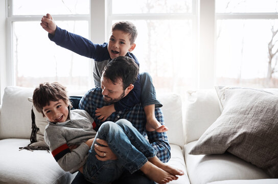 Dad with boy children, playing and energy with fun, carefree with love and laughter at family home. Man play with kids laughing in living room, crazy and playful with piggyback, hug and excited