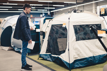 A young man examines a tent in a store. © Nataliya