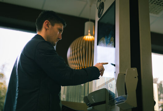 A Young Man Makes An Order For Fast Food On A Scoreboard Screen In A Diner.