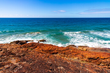 Fototapeta na wymiar red cliff in deepwater national park near agnes water in queensland, australia; red rocks above turquoise water