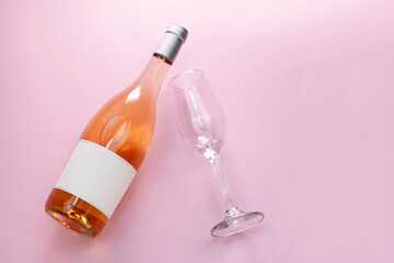 Wine bottle mockup, unopened bottle of rose wine and a glass on pink background, top view, copy space, flat lay