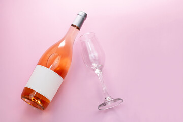 Wine bottle mockup, unopened bottle of rose wine and a glass on pink background, top view, copy space, flat lay