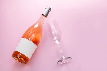 Wine bottle mockup, unopened bottle of rose wine and a glass on pink background, top view, copy...