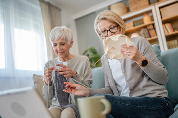 two women senior mature knitting and embroidery during leisure time