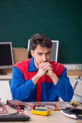 Young male repairman repairing computers in the classroom