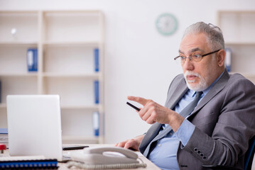 Old male employee working in the office