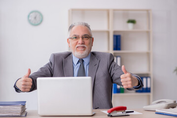 Obraz premium Old male employee working in the office