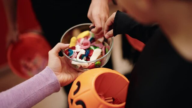 Group of kids wearing halloween costume receiving candies at home