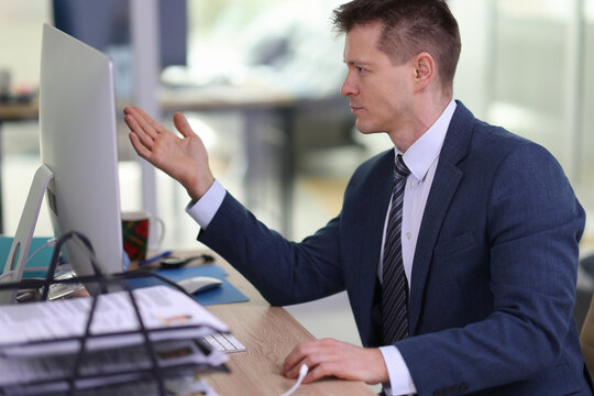 Disappointed employee looks at computer monitor at workplace