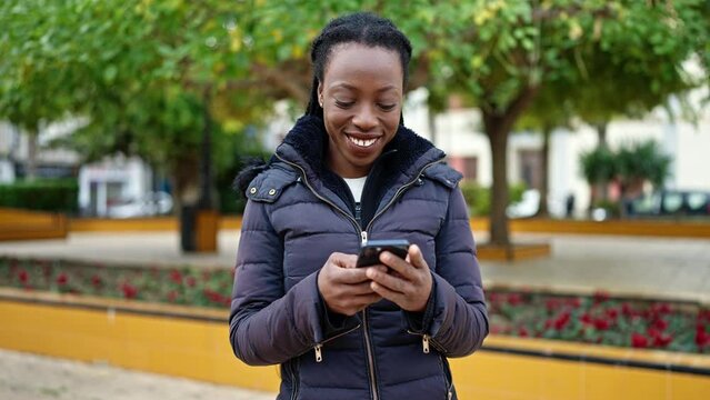 African american woman smiling confident using smartphone at park