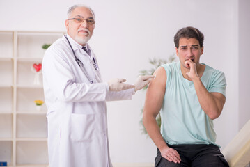 Obraz premium Young male patient visiting old male doctor in vaccination conce