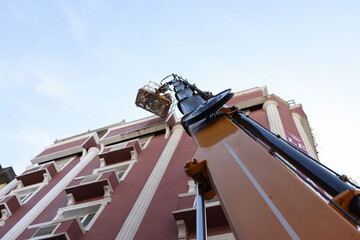 Construction cradle on crane hoist near restoring building