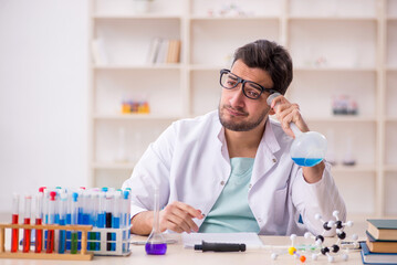 Young male chemist sitting at the lab