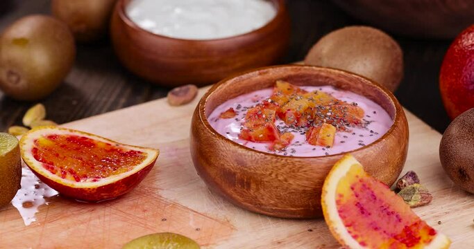 add chia seeds to fresh yogurt with berries and fruits with red oranges, delicious dessert yogurt with orange flavor and pieces of fruit