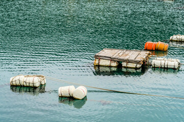 Styrofoam floats and wooden dock floating in water.