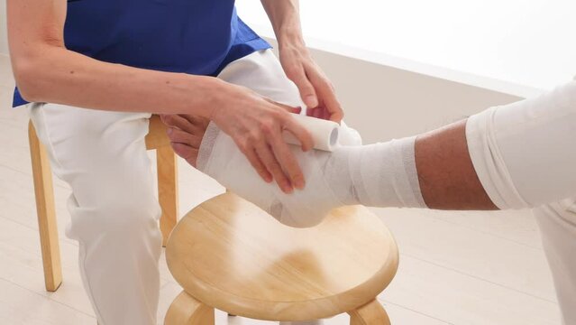 足首に包帯を巻く看護師　顔無し