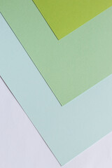 Sheets of paper of green shades lie on the table with corners in one direction.