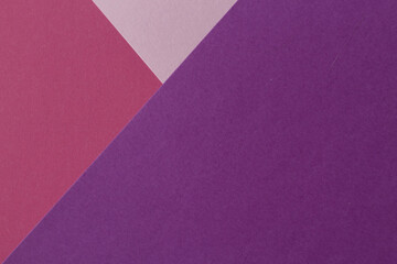 Pink, burgundy and purple paper lie on the table in a geometric composition