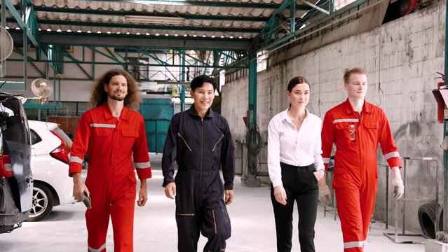 A team of male mechanics at the garage in red uniforms. and female customers walking in the car repair They all folded their arms to show their commitment to work. to repair cars for customers