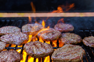 On hot grill barbecued American beef burger is being grilled in flames