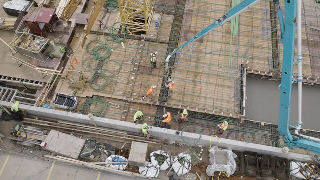 Aerial, construction workers using concrete pump to pour foundation through rebar support