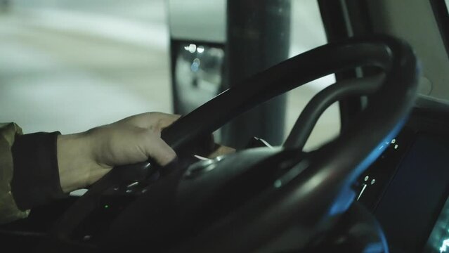 Close up, anonymous truck or bus driver steering wheel, driving at night