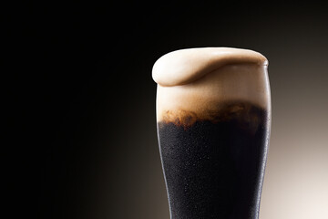 黒ビール、水滴のついたグラスから泡が溢れる冷えたビール - obrazy, fototapety, plakaty