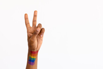 Cropped image of african american man with rainbow flag paint of hand showing victory sign over wall