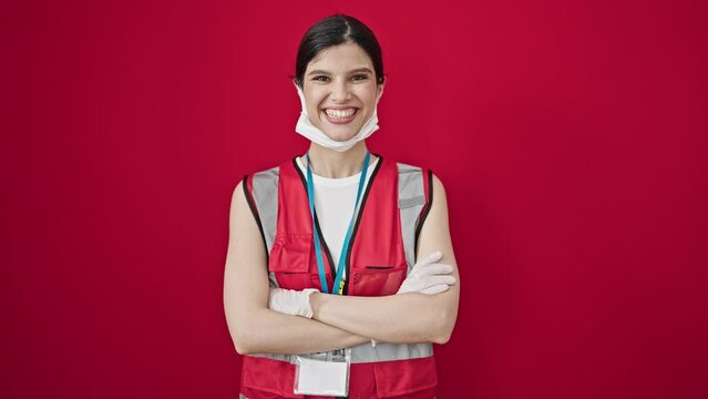 Young beautiful hispanic woman doctor wearing medical mask standing with arms crossed gesture over isolated red background