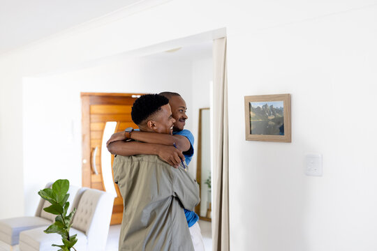 Loving african american young gay couple embracing and looking at picture frame hanging on wall