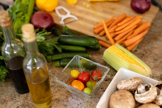 High angle view of carrots, cucumbers, corn, mushrooms, celery, cooking oil on kitchen island